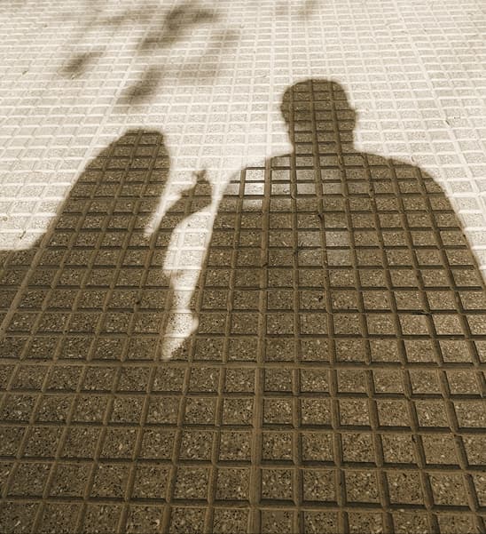 Silhouettes of two people cast in shadow on a gridded surface
